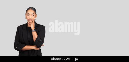 A poised young woman with a contemplative expression stands confidently Stock Photo