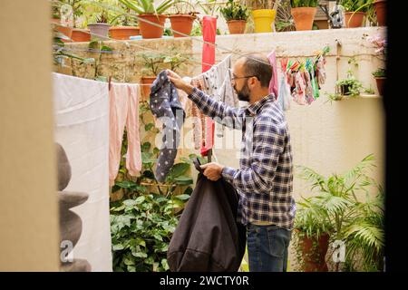 Young man doing housework. Man hanging clothes. Stock Photo
