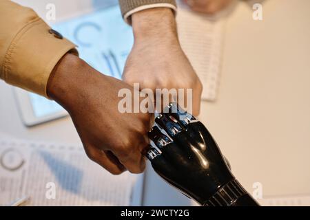 Unknown biracial coworkers and their colleague with prosthesis making fist bump to each other Stock Photo