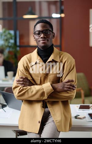 Young african american office worker in smart casual outfit confidently posing against his workplace Stock Photo