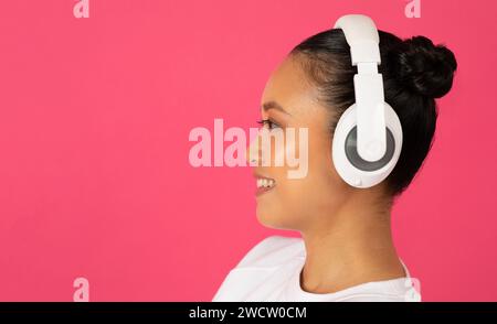 Side view of young asian woman wearing stylish wireless headphones Stock Photo