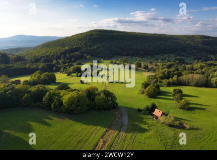idyllic nature landscape with meadow and cottage in green hills mountain from drone Stock Photo