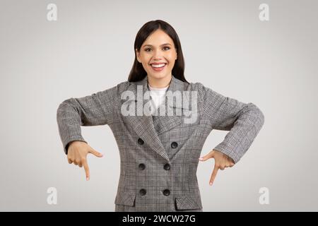 Happy woman in a jacket pointing down with both hands Stock Photo