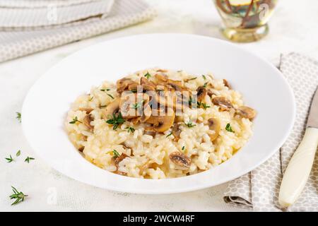 Dish with delicious risotto with mushrooms in plate. Rice porridge with fungus and tmyne. Hot dish, italian cuisine. Stock Photo