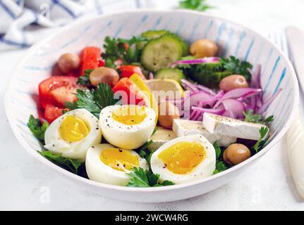 Breakfast. Greek salad and boiled eggs. Fresh vegetable salad with tomato, cucumbers, olives, arugula and cheese. Stock Photo