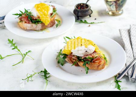 Breakfast. Sandwich with ham, poached egg, onion and arugula in a plate on a light background Stock Photo
