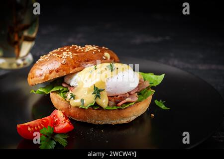 Breakfast. Sandwich with ham, poached egg, onion and arugula in a plate on a dark background Stock Photo