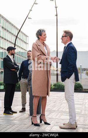 Vertical. Handshake between businessman and corporate woman at workplace. Business people. Professional colleagues talking and greeting at startup meeting. Agreement or deal of two executive workers. High quality photo Stock Photo