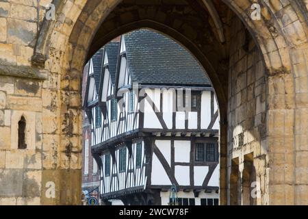 Lincoln, Lincolnshire, England. View through 14th century Exchequer Gate to half-timbered Leigh-Pemberton House, now a visitor centre. Stock Photo