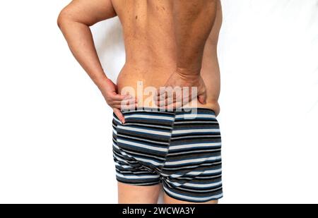 Close up of an elderly person with back pain in the lower spine isolated in white. Stock Photo