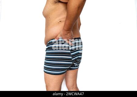 An older man suffering from sciatica back pain on the left side isolated in white. Stock Photo