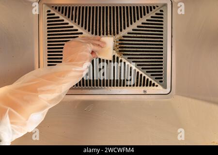 cleaning an oily filter hood by sponge from a kitchen ventilator Stock Photo