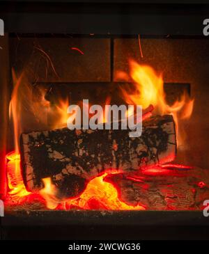 Close-up view of a burning log in a fireplace with vibrant flames and glowing embers Stock Photo