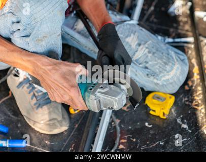Building contractor is cutting lightweight metal, steel, edge trim with an electric angle grinder Stock Photo
