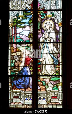 France, Moselle, Delme, St. Germain church built in 1859 in neogothic style, stained glass window made in 1923 by masters glassmakers Ott Freres (Brothers) workshop of Strasbourg representing the Apparition of Virgin Mary to St Bernadette Soubirous in Lourdes Stock Photo