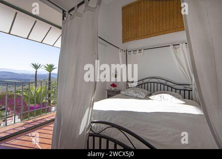 Spain, Andalusia, Moron de la Frontera, hacienda las Alcabalas, suite with a four-poster bed and a garden planted with tall palm trees and hills Stock Photo