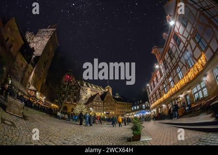 NUREMBERG, GERMANY - DECEMBER 16, 2023: Night view with tourists relaxing on medieval Tiergärtnertor Square, old town. Stock Photo