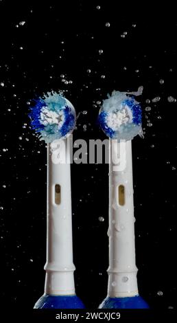 Electric toothbrushes with water splashes on black background. Close-up. Stock Photo