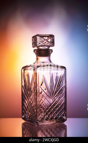 Empty decanter for whiskey on a blue-orange gradient background. Colors blend seamlessly with a haze effect. Stock Photo