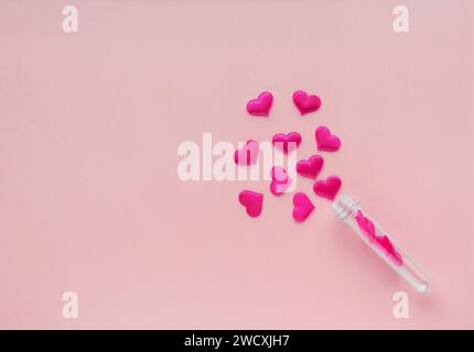 Fabric hearts from a test tube on a pink background. Stock Photo