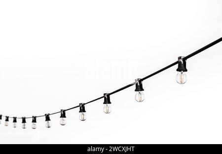 Incandescent bulbs on a black wire on a white background Stock Photo