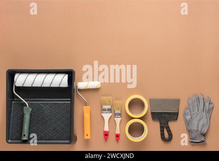 Set of tools for painting on a beige background. Rollers, brushes, masking tape, spatulas and gloves. Repair process. Stock Photo