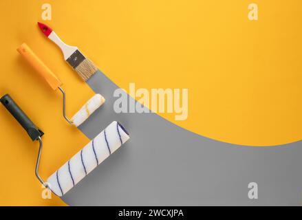 Gray stripes of paint from rollers and brushe on a yellow background. Home renovation concept. Stock Photo