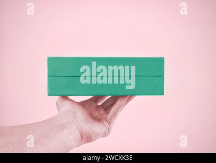 Man holds gift box on pink background. Pastel colors. Gift giving concept. Stock Photo