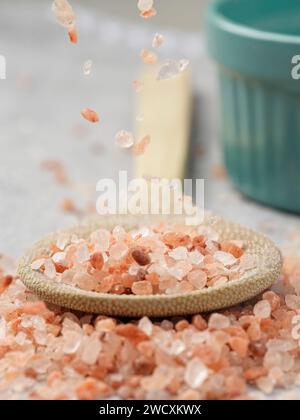 Concept photo of coarse himalayan pink salt falling down onto a wooden spoon. Stock Photo