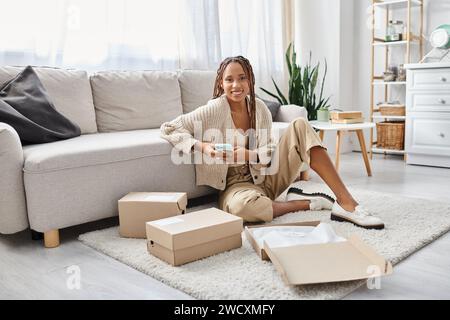 cheerful attractive african american woman with phone in her hands smiling joyfully at camera Stock Photo