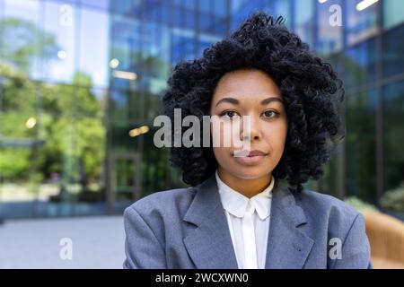 Portrait of a serious African American female student standing outside campus wearing a suit and looking confidently at the camera. Close-up photo. Stock Photo