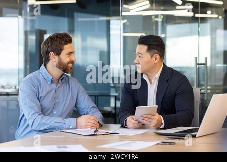Two professional businessmen collaborating in a modern office setting. Work discussion between colleagues in the corporate world. Stock Photo