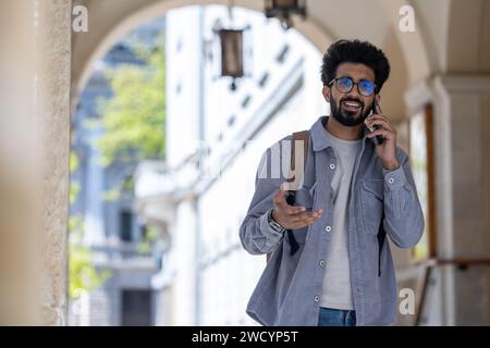 Dark-haired man walking through the arch and talking on the phone Stock Photo