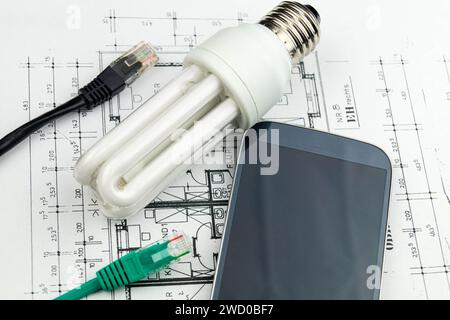 Energy-saving lamp, smart phone and network plug on construction drawings, symbolic image for smart home Stock Photo
