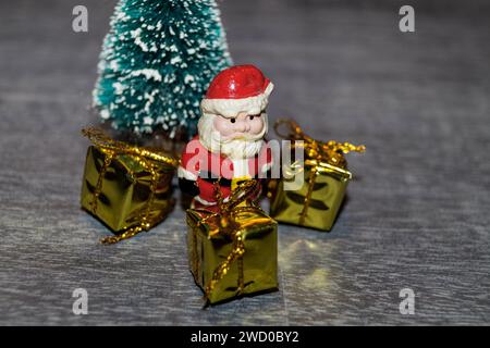 Christmas decorations consisting of Santa Clauses, Christmas tree and golden presents on the table Stock Photo