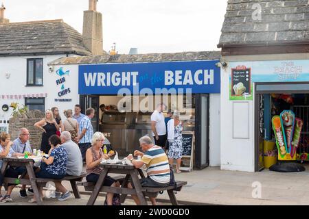 Fish and Chips takeaway restaurant on the beach in Swanage,Isle of Purbeck,Dorset, with people sitting eating at wooden tables,England,UK,2023 Stock Photo