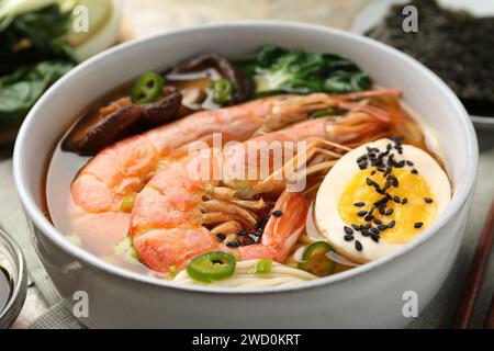 Delicious ramen with shrimps and egg in bowl on table, closeup. Noodle soup Stock Photo