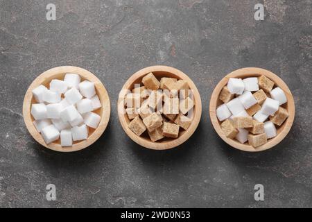 Different sugar cubes in bowls on gray textured table, flat lay Stock Photo