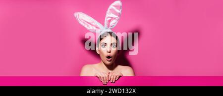 Easter banner with bunny woman. Funny emotions, excited expressing. Bunny woman isolated on pink. Stock Photo