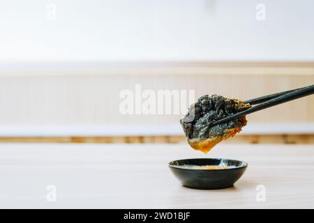 Fried Black Gyoza is taken using black chopsticks with bokeh background. Close up shot. Stock Photo