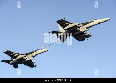 An F/A-18E Super Hornet, right, refuels an EA-18G Growler. Stock Photo