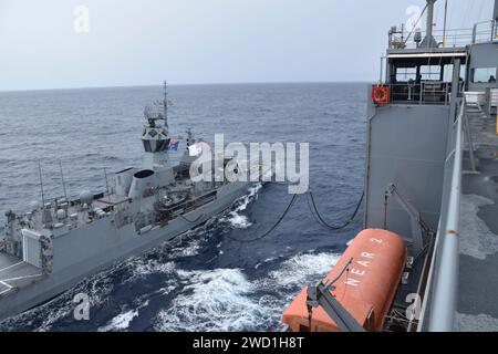 The Royal Australian Navy frigate in the HMAS Ballarat alongside dry cargo ship USNS Amelia Earhart. Stock Photo