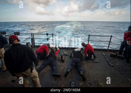 Sailors fire M240 light machine guns on the fantail of the aircraft carrier USS Theodore Roosevelt. Stock Photo