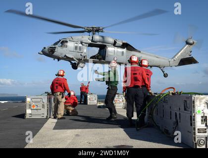 Sailors load ammunition onto an MH-60S Sea Hawk on the flight deck of USS Nimitz. Stock Photo