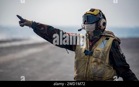 Aviation Boatswain's Mate directs aircraft on the flight deck of USS Carl Vinson. Stock Photo