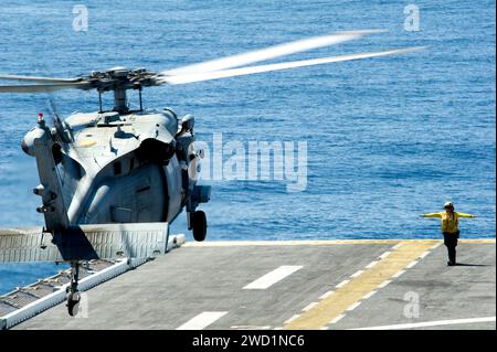 Aviation Boatswain's Mate guides an SH-60 Seahawk as it lands on the flight deck of USS America. Stock Photo