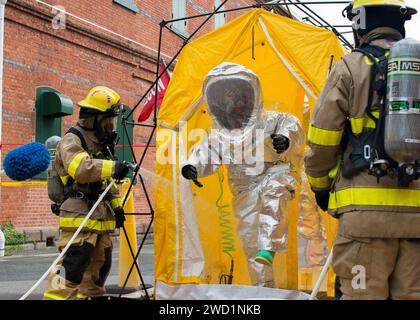 Fire and emergency services personnel spray and decontaminate a fire proximity suit. Stock Photo
