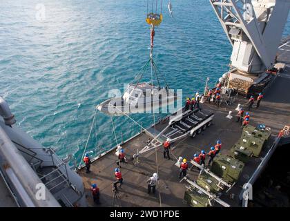 Sailors lower a rigid-hull inflatable boat from the amphibious dock landing ship USS Ashland. Stock Photo