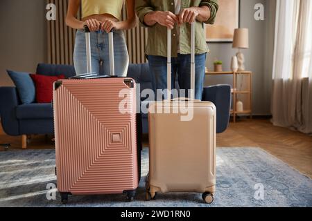 Crop of family couple going for trip posing with packed luggage suitcases at home Stock Photo