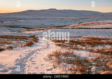 A beautiful distant view of Ingleborough in the Yorkshire Dales National Park at sunset on a snowy winter day, with crisp clear skies in January 2024. Stock Photo